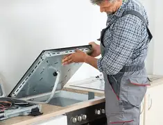 Appliance repair technician installing a built-in cooktop in Tempe, AZ