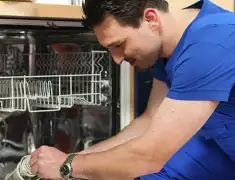 Dishwasher repair technician inspecting and servicing an open dishwasher in Tempe, AZ