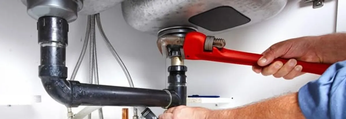Garbage disposal repair technician tightening the sink drain and disposal connection in Tempe, AZ