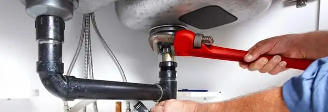 Garbage disposal repair technician tightening the sink drain and disposal connection in Tempe, AZ