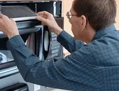 Appliance repair technician replacing a microwave vent filter in Tempe, AZ