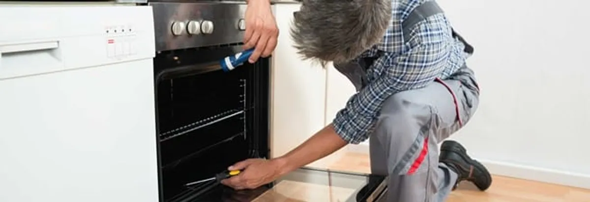 Oven repair technician inspecting and servicing an electric oven in Tempe, AZ