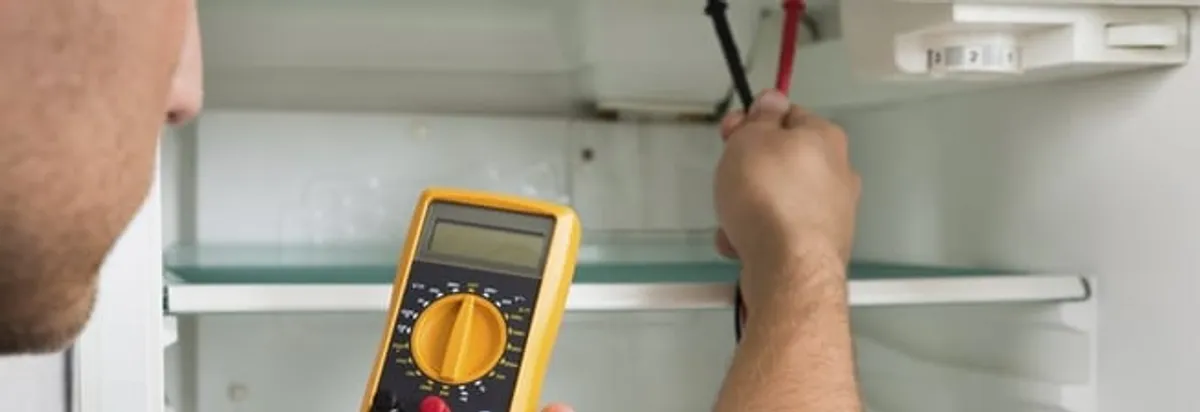 Refrigerator repair technician testing electrical components with a multimeter in Tempe, AZ