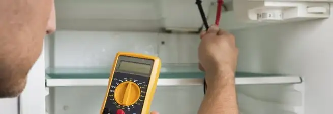 Refrigerator repair technician testing electrical components with a multimeter in Tempe, AZ