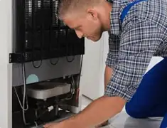 Refrigerator repair technician servicing the compressor and condenser area in Tempe, AZ