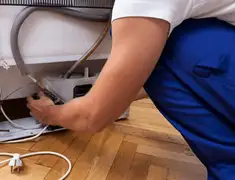 Appliance repair technician fixing refrigerator water line and connections in Tempe, AZ
