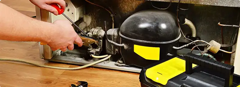 Refrigerator repair technician fixing the compressor and wiring in Tempe, AZ