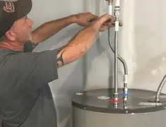 Water heater repair technician tightening supply line connections in Tempe, AZ