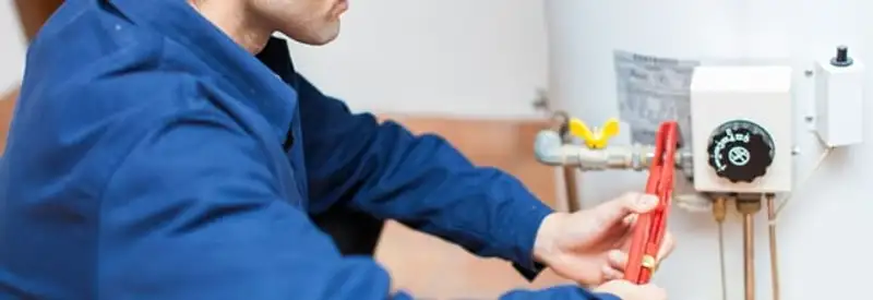 Water heater repair technician adjusting the temperature control and gas valve in Tempe, AZ